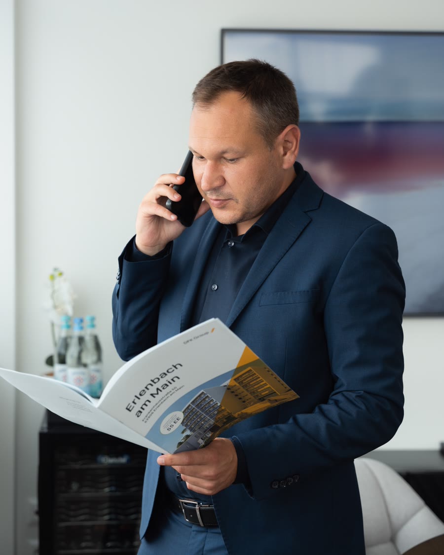 Viktor Evseev telefoniert mit einem Exposé in der Hand